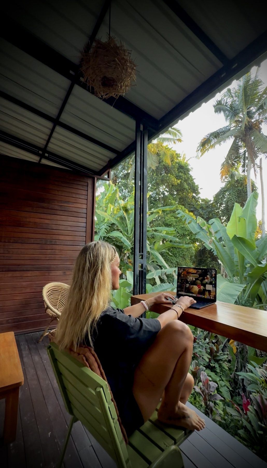 Angelina arbeitet auf einer Terrasse im Grünen am Laptop
